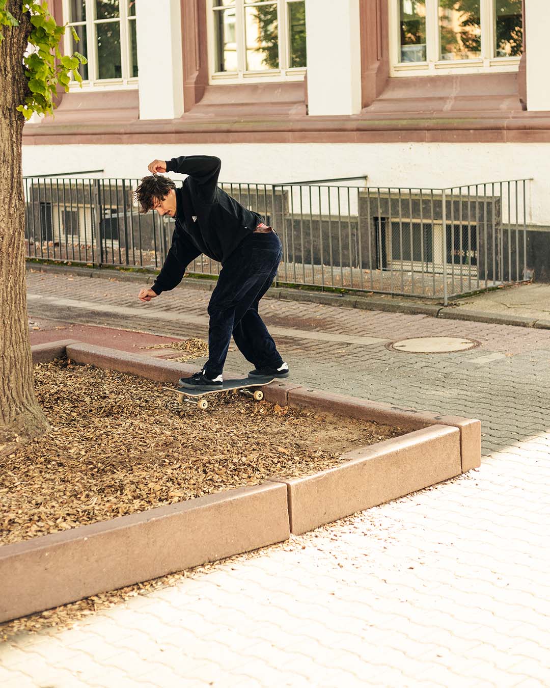 Still photo of skateboarder Tim Janke performing a Backside Tailslide on the inside of a brown curb.