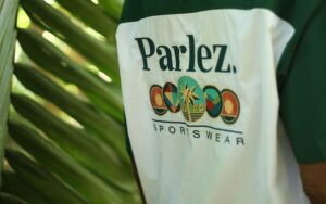 Image showing a green Parlez jacket in front of palm trees along with dates for the event.