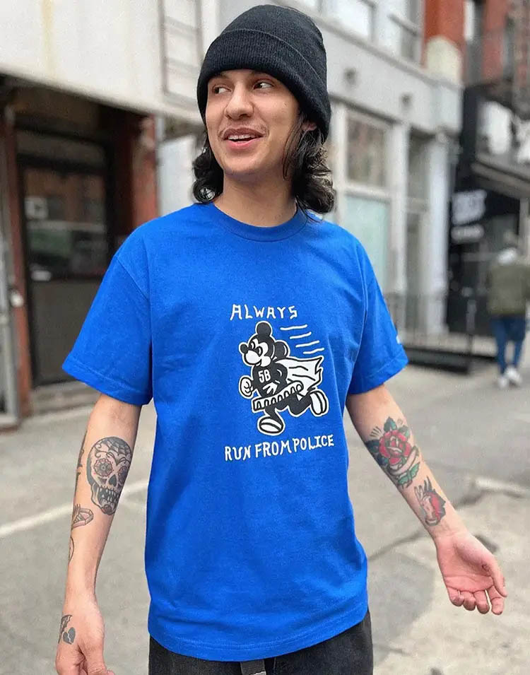 Young male model in the streets of New York wearing a blue t-shirt showing a Micky Mouse print and saying always run from police