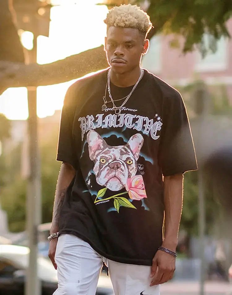 Sundown portrait of young professional skateboarder Robert Neal, wearing chains and a black Primitive t-shirt with a massive print showing a French bulldog