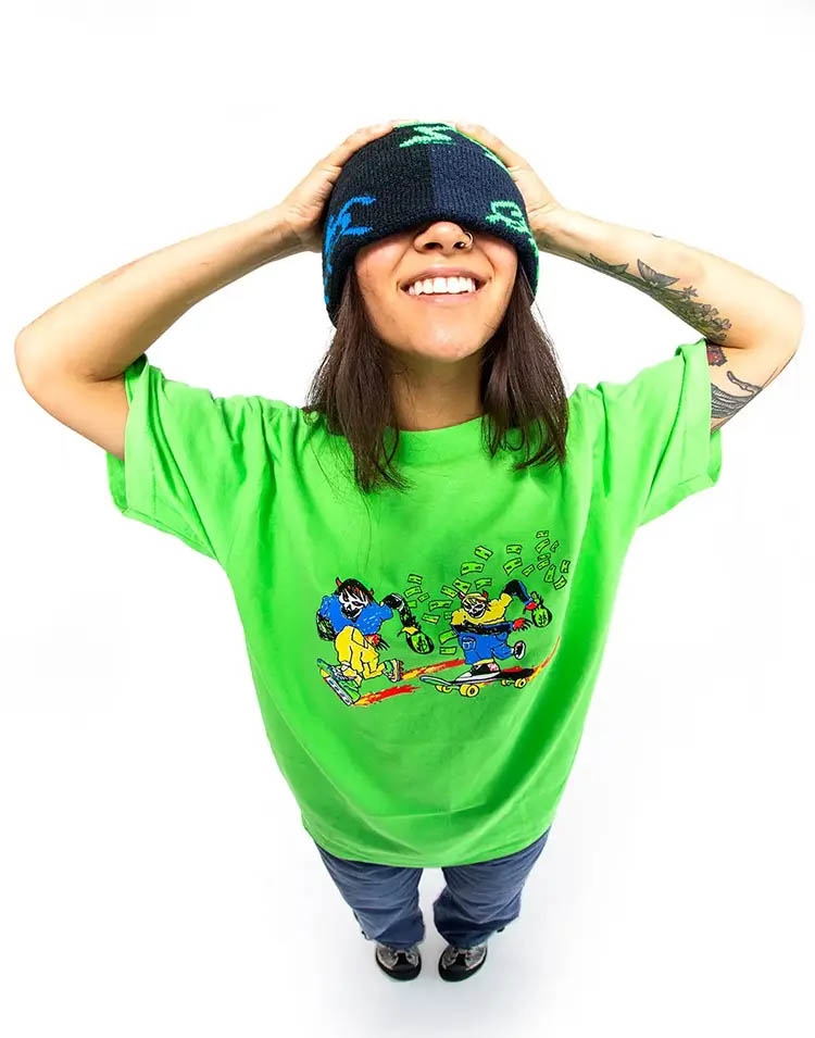 Female model covering her eyes funnily with a wool beanie and wearing a neon green Weekend shirt with a comic graphic
