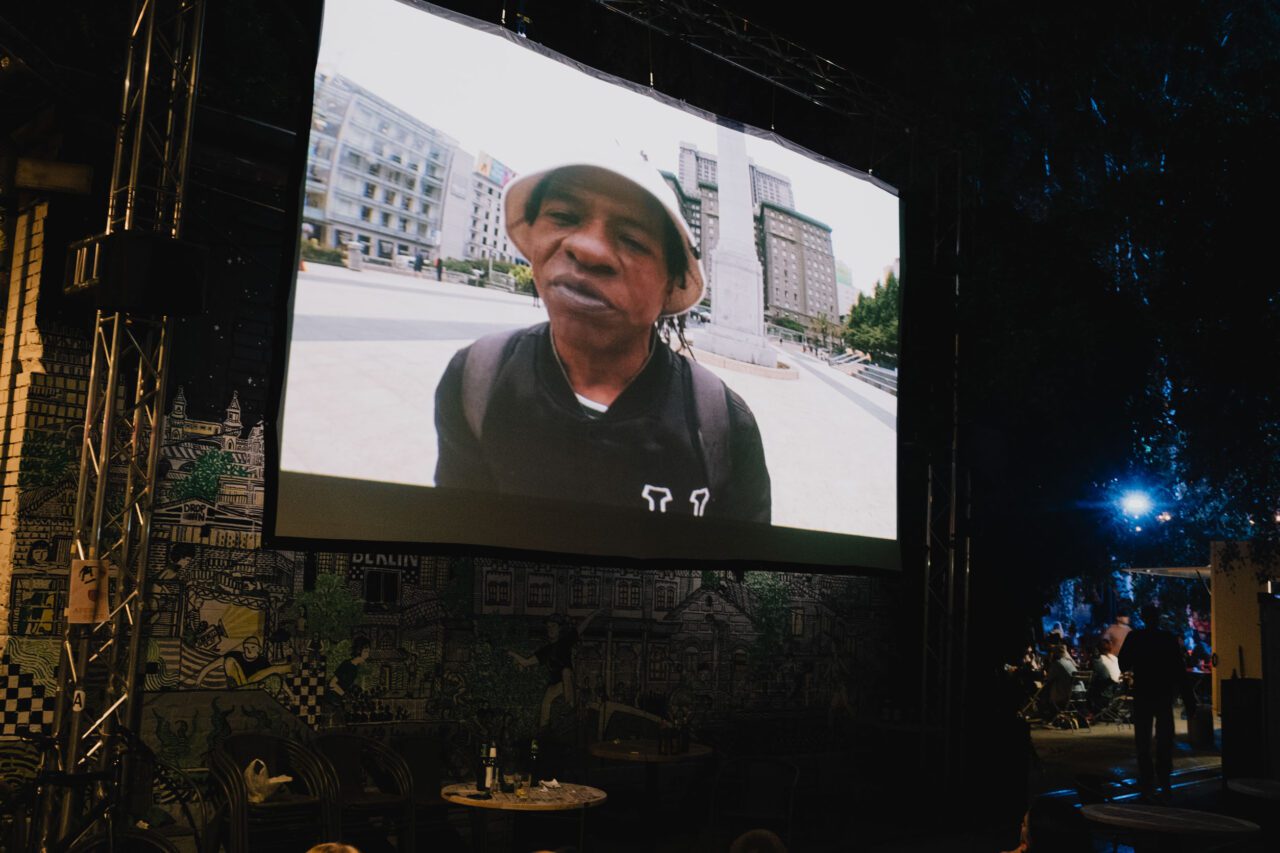 Photo showing a big movie screen showing a scene from HUF's latest movie "Forever".