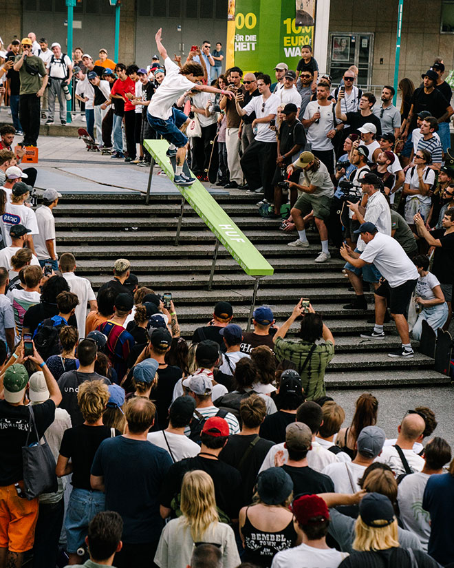 Photo of Jelle Maatman doing a Frontside Nosegrind down a gnarly handrail with a green topper during the HUF “Rail around the corner” event at SKTWK 2023.