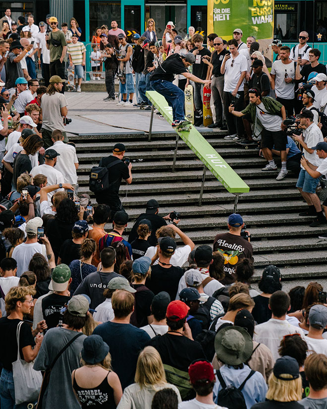Photo of Alex Sorgente doing a Frontside 5-0 down a gnarly handrail with a green topper during the HUF “Rail around the corner” event at SKTWK 2023.