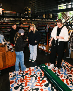 Portrait of a group of young people gathering around a training golf matte, inside of Erfurt’s Orange Jungle shop.