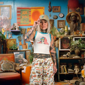 Mood photography of a young woman with blonde hair and tattoos, facing the camera and wearing clothing by a Berlin based label called The Dudes.