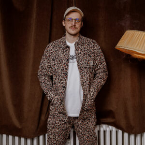 Mood photography of a young man, wearing a button up and short with the same allover pattern design from Berlin based streetwear label called The Dudes.